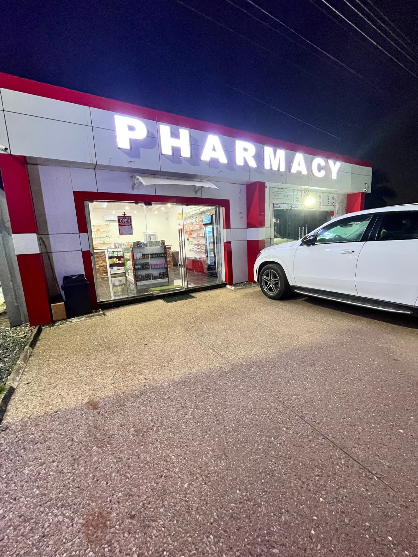 Amex Pharmacy storefront lit up at night in Accra